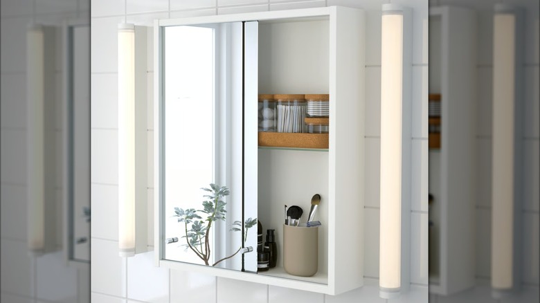IKEA mirror cabinet with bathroom organizers, a toothbrush holder, and small bathroom products