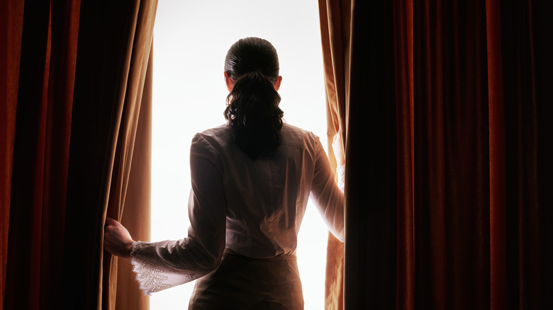 a woman parts velvet drapes