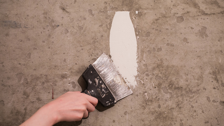 Person applying a skim coat to a rough concrete surface