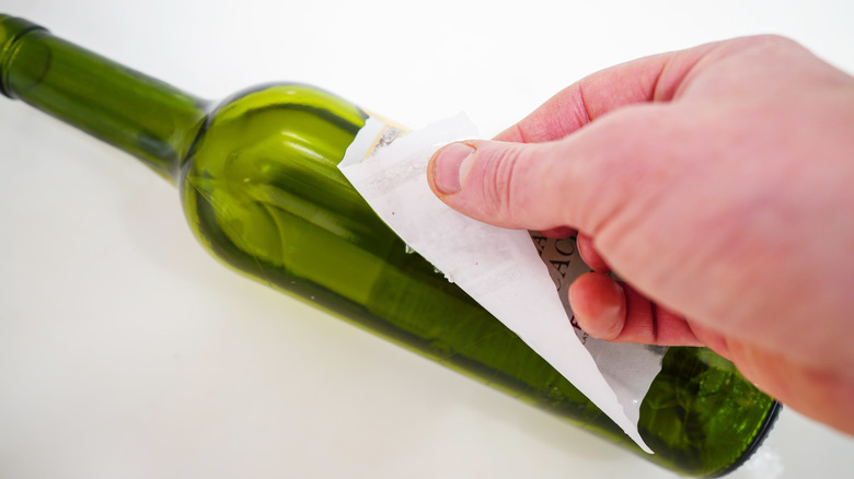 peeling a label off of a wine bottle