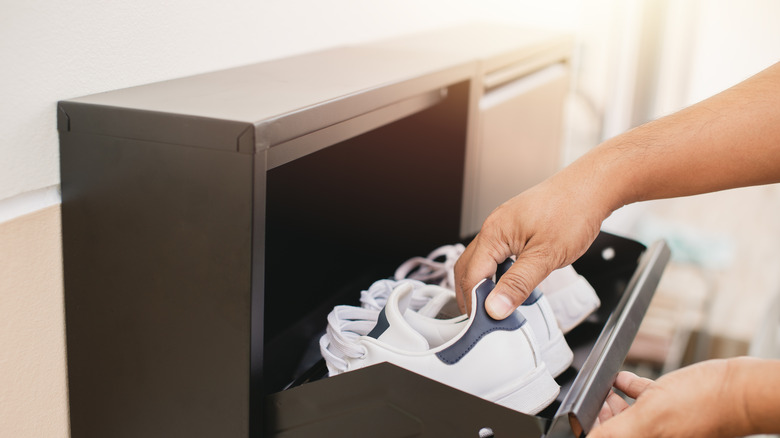 A man places a pair of shoes in a shoe cubby.