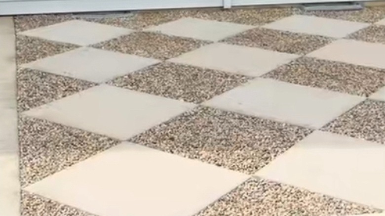 Patio with gravel and concrete pavers in front of a house with white siding