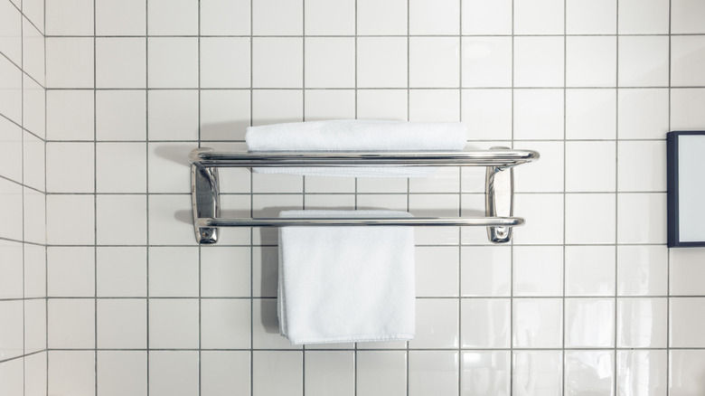 A white towel hanging on towel rack in modern tiled bathroom