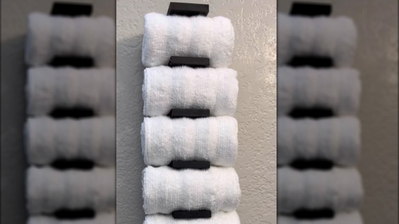 DIY towel rack made from a wood sign and wood blocks holding white towels