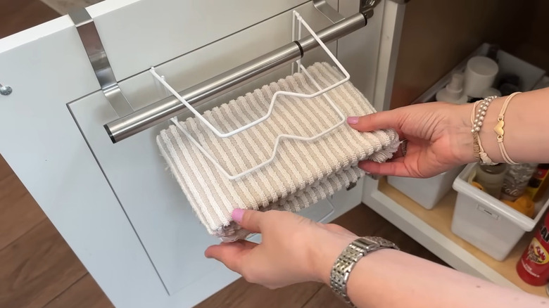 Person sliding a folded towel on a DIY over-the-door holder
