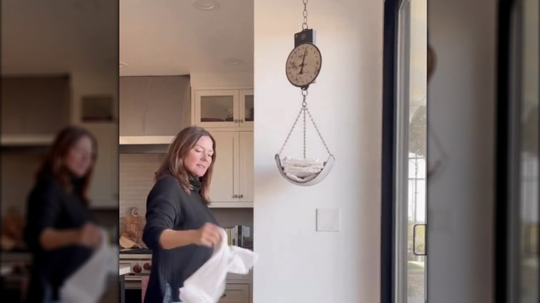 Woman grabbing a towel off of a hanging scale in the kitchen