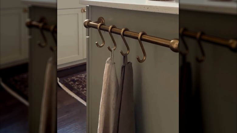 Towels hanging on hooks over a towel bar on the side of a cabinet