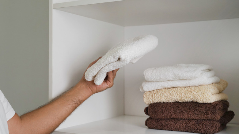 Person stacking towels on a shelf