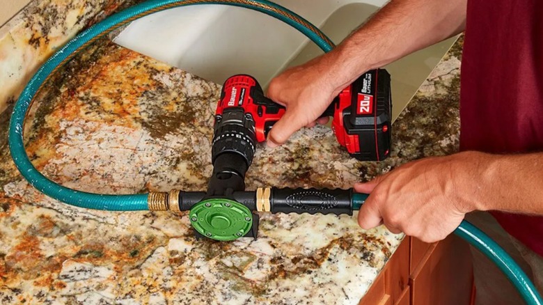 Person using drill and drill pump to empty sink