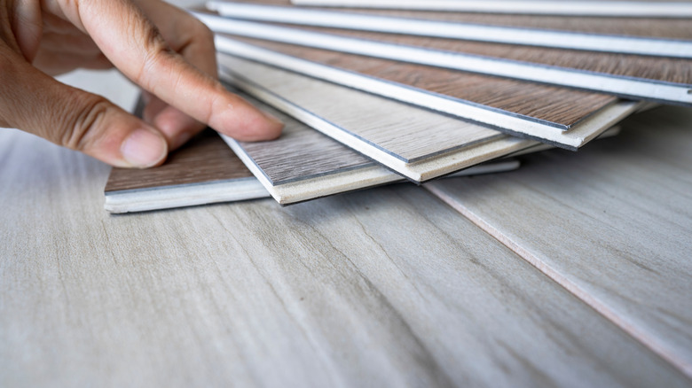 close up of hand looking through vinyl wood tile samples