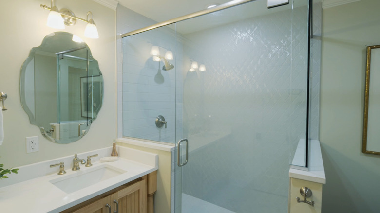 A bathroom with a double vanity and a shower with mosaic tiles that mimic a leaf shape