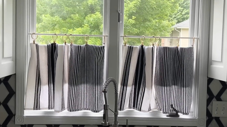 Black and white tea towels hanging as curtains in a kitchen window