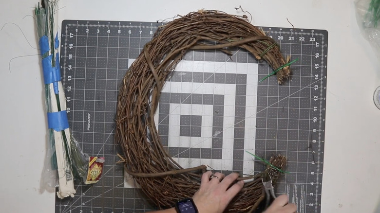 Hands trimming crescent grapevine wreath