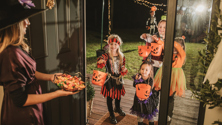 A person greeting trick or treaters at the front door