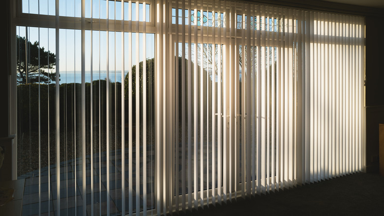 White vertical blinds over large glass doors