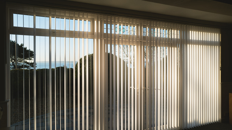 Sunshine coming through vertical blinds over a sliding glass door