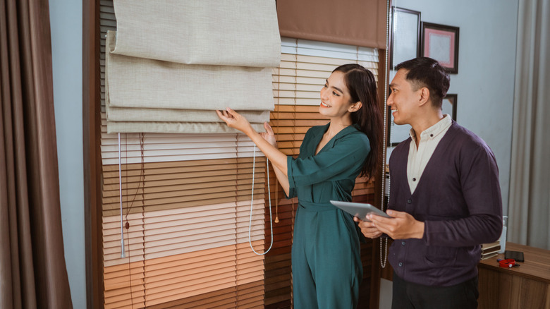 couple shopping for window treatments and looking at a woven Roman shade