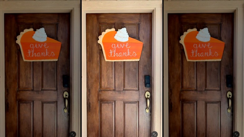 A front door with a Thanksgiving sign in the shape of pumpkin pie.