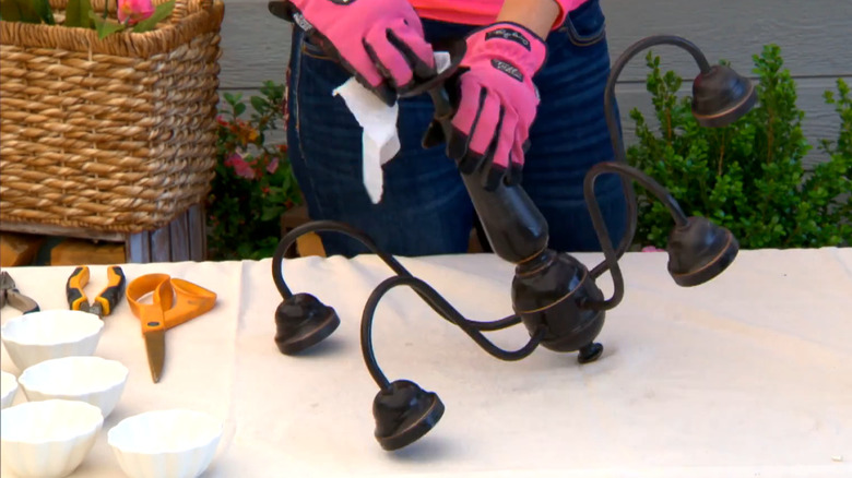 Woman transforming old chandelier into bird feeder