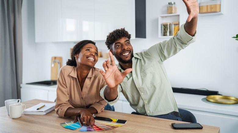 Smiling couple envisioning renovations while looking at color swatches and taking notes