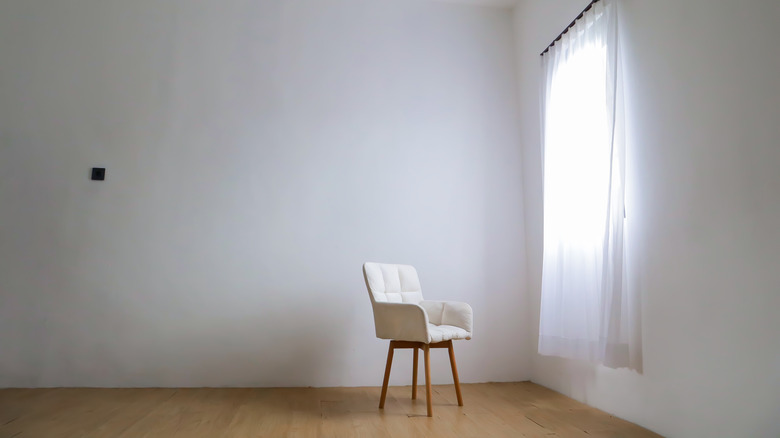 chair sitting in front of blank, boring wall