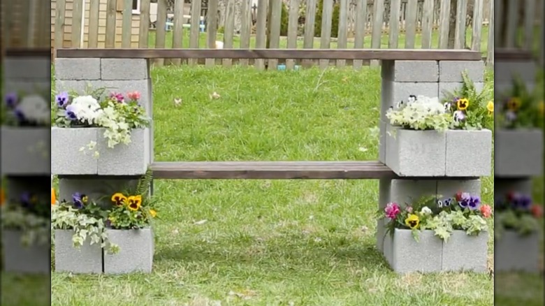 Cinder block bar with wood plank shelf and top and flowers planted in the blocks
