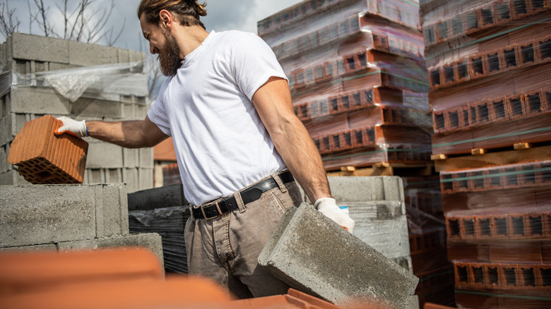 Man picking up cement blocks