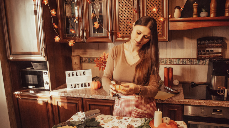 A woman creates paper decor in a fall themed kitchen