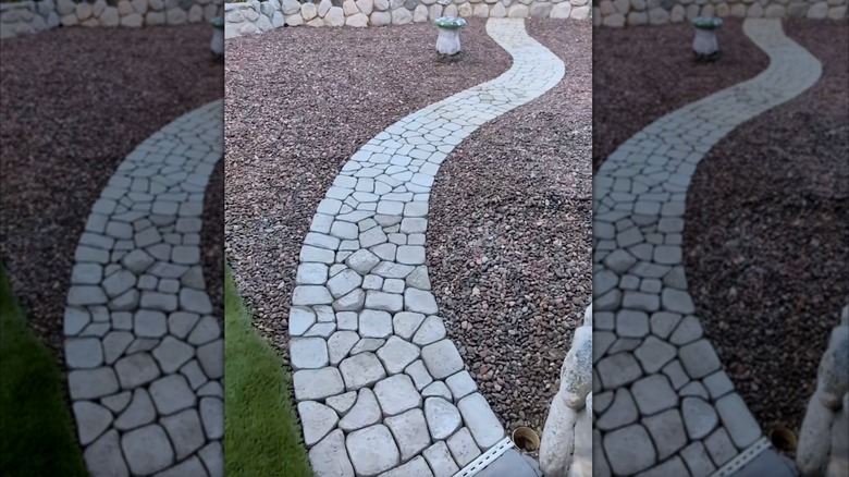 A DIYed winding faux-cobblestone pathway made of poured cement in milk jug molds