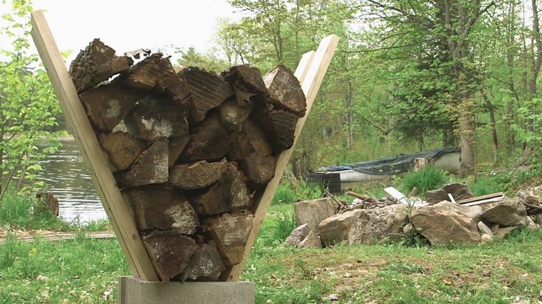 Firewood stand with V-shaped supporting boards in a cinder block base