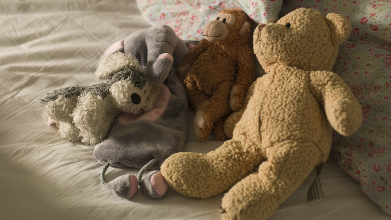 teddy bear, stuffed monkey, elephant stuffy, and dog stuffed animal resting on a bed