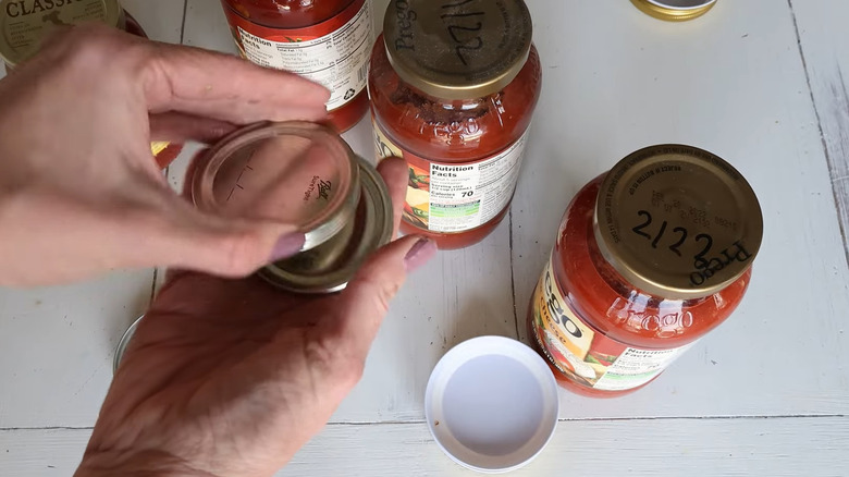 Person holding lids with additional jars in the background