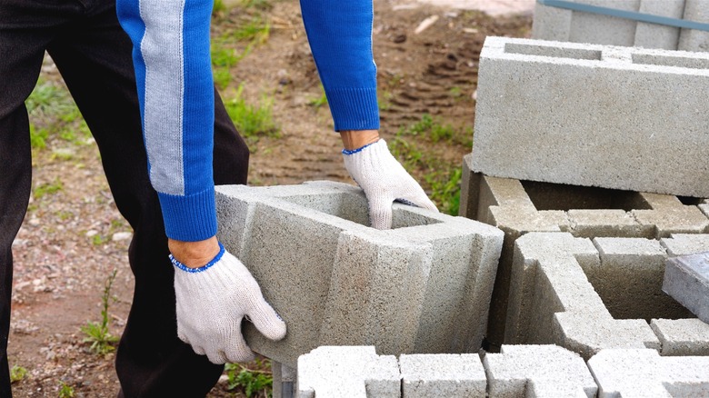 Person moving concrete blocks from a stack