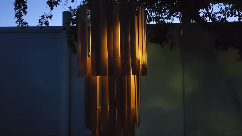 A chandelier made from a tomato cage and wood shims lights up at night