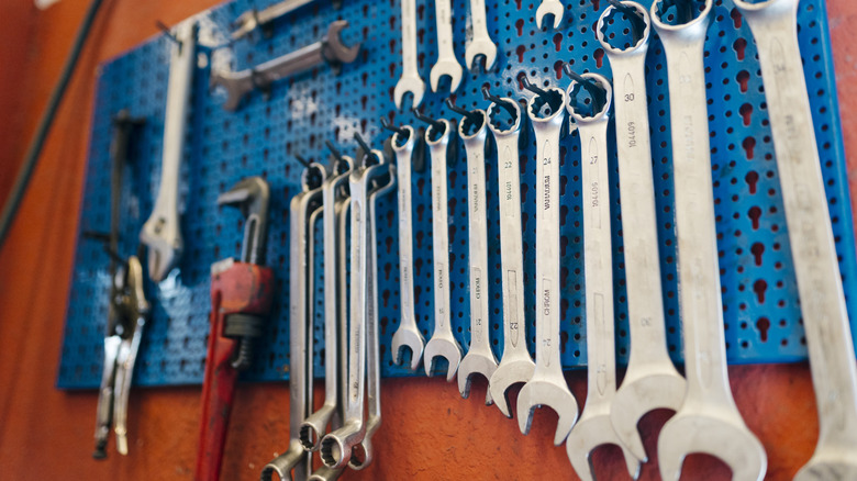 tools hanging on a metal pegboard panel