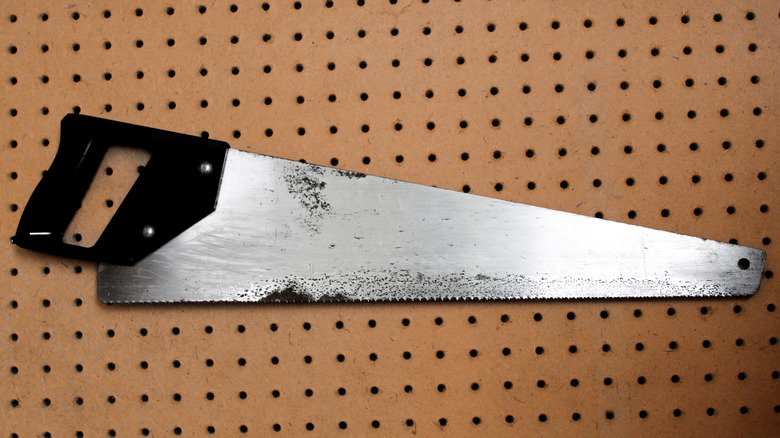 Saw hanging on a hardboard pegboard panel