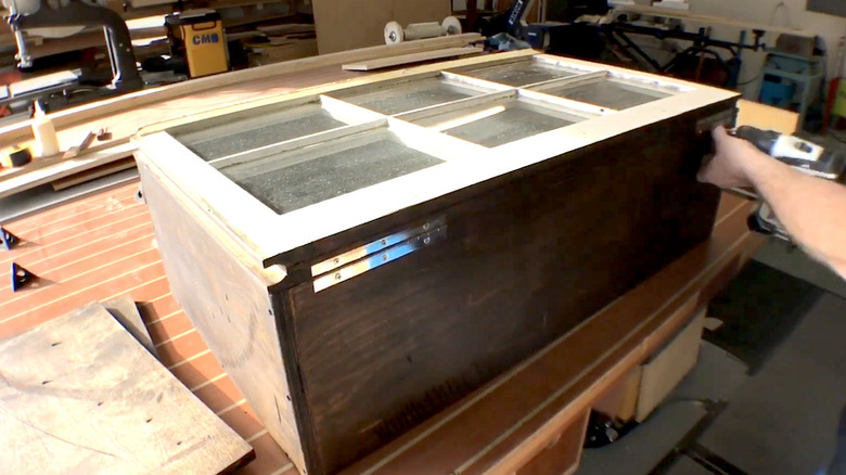 A cabinet being made out of an old window pane lying on a wooden table.