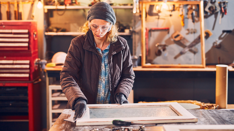 A woman working on an old window in a workshop
