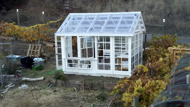 A greenhouse made out of old windows in a yard.