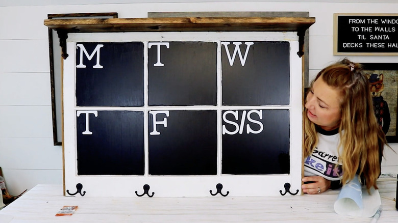 A woman looking at a chalkboard made from a old window pane.