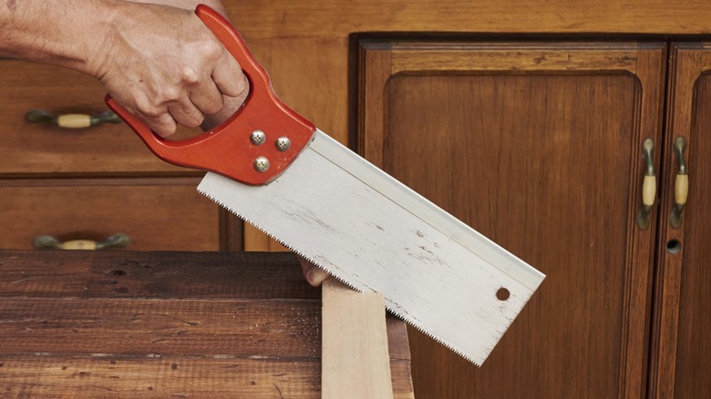 Woodworker cutting a pine board with a tenon saw