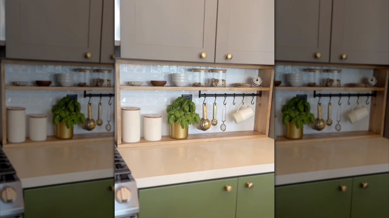 A green kitchen cabinet with a wooden DIY shelving unit in a modern kitchen