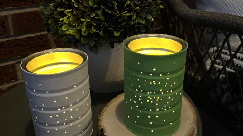 Empty soup can with holes punched in it and a tealight inside on a patio