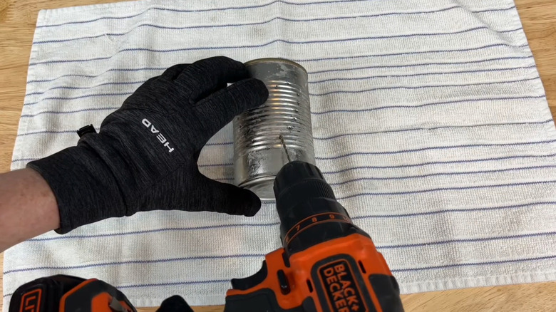 A person drills into a soup can