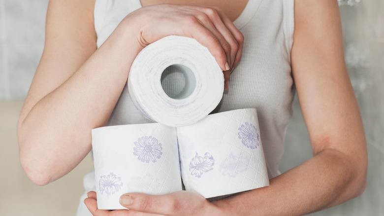A person holding rolls of toilet paper