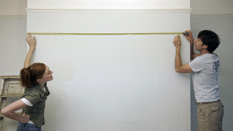 A couple measuring a blank wall