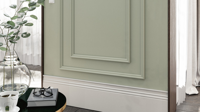 close up of double layer green wall trim molding and green wall and a potted plant
