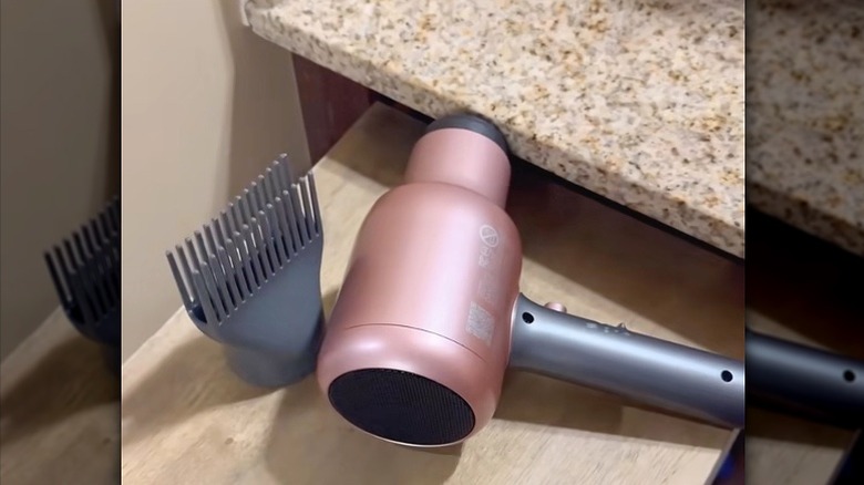 A bathroom drawer with plywood counter extender on top holding a blowdryer and accessories