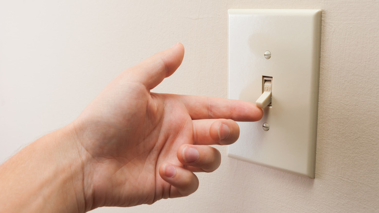 Finger touching light switch with basic cover