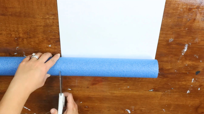 Woman cutting a blue pool noodle with a pair of scissors